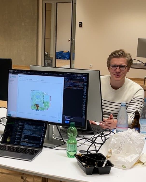 Teammitglied am Arbeitstisch im Büro am Launch-Tag, auf dem Monitor ein Lageplan