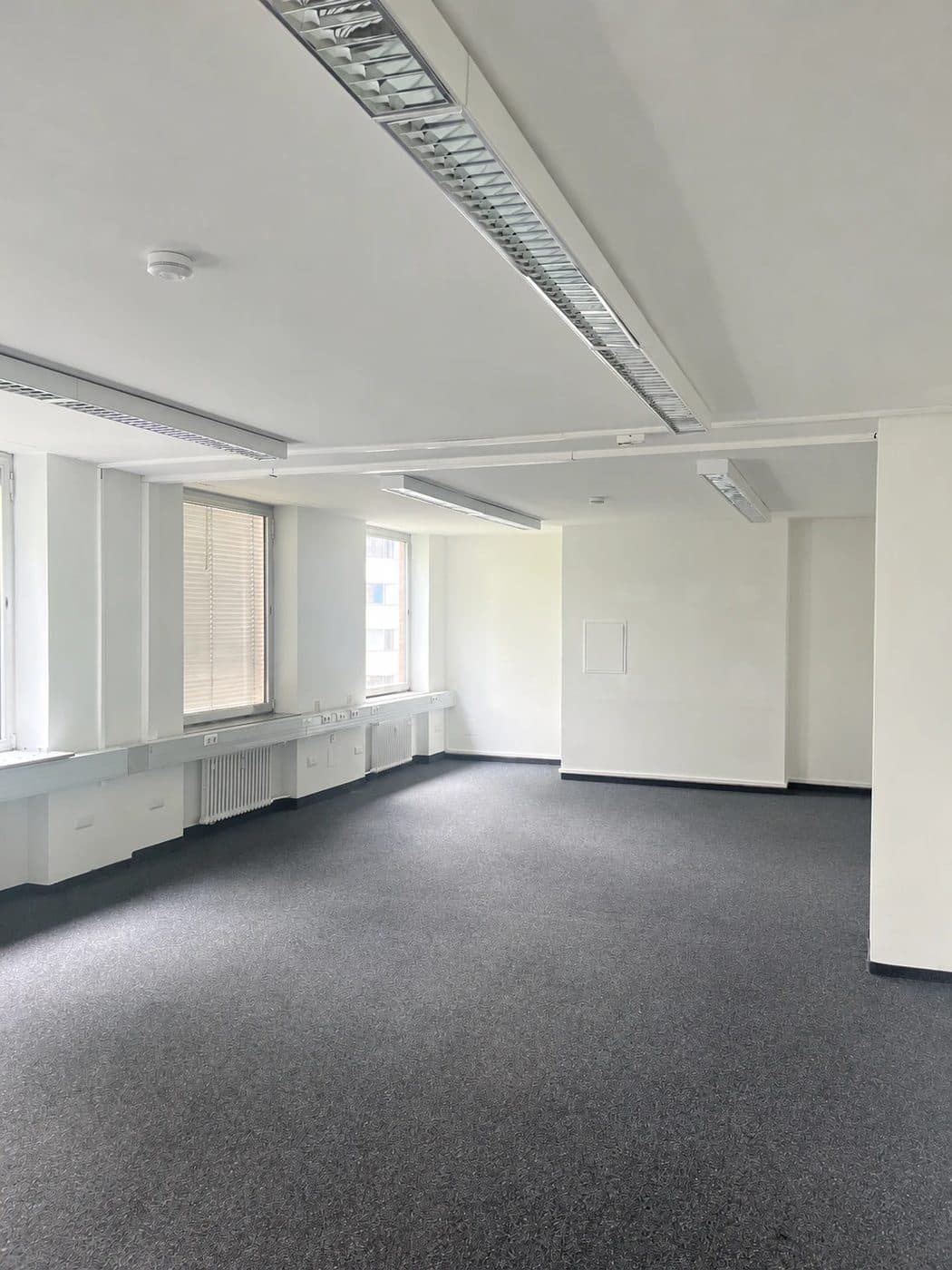 Leeres neues Büro mit Teppichboden und Fensterfront vor dem Einzug